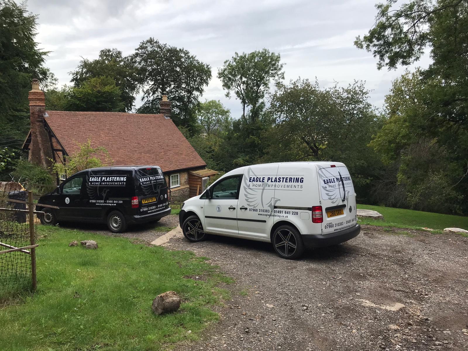 Eagle Plastering & Home Improvements' branded work vans outside a period Oxfordshire cottage